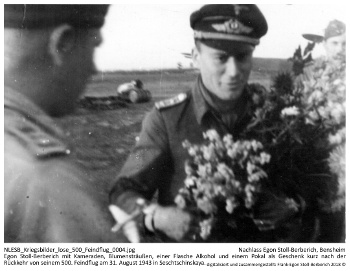 Egon Stoll-Berberich mit Kameraden, Blumensträußen, einer Flasche Alkohol und einem Pokal als Geschenk kurz nach der Rückkehr von seinem 500. Feindflug am 31. August 1943 in Seschtschinskaya. NLESB_Kriegsbilder_lose_500_Feindflug_0004. Egon Stoll-Berberich mit Kameraden, Blumensträußen, einer Flasche Alkohol und einem Pokal als Geschenk kurz nach der Rückkehr von seinem 500. Feindflug am 31. August 1943 in Seschtschinskaya. NLESB_Kriegsbilder_lose_500_Feindflug_0004.