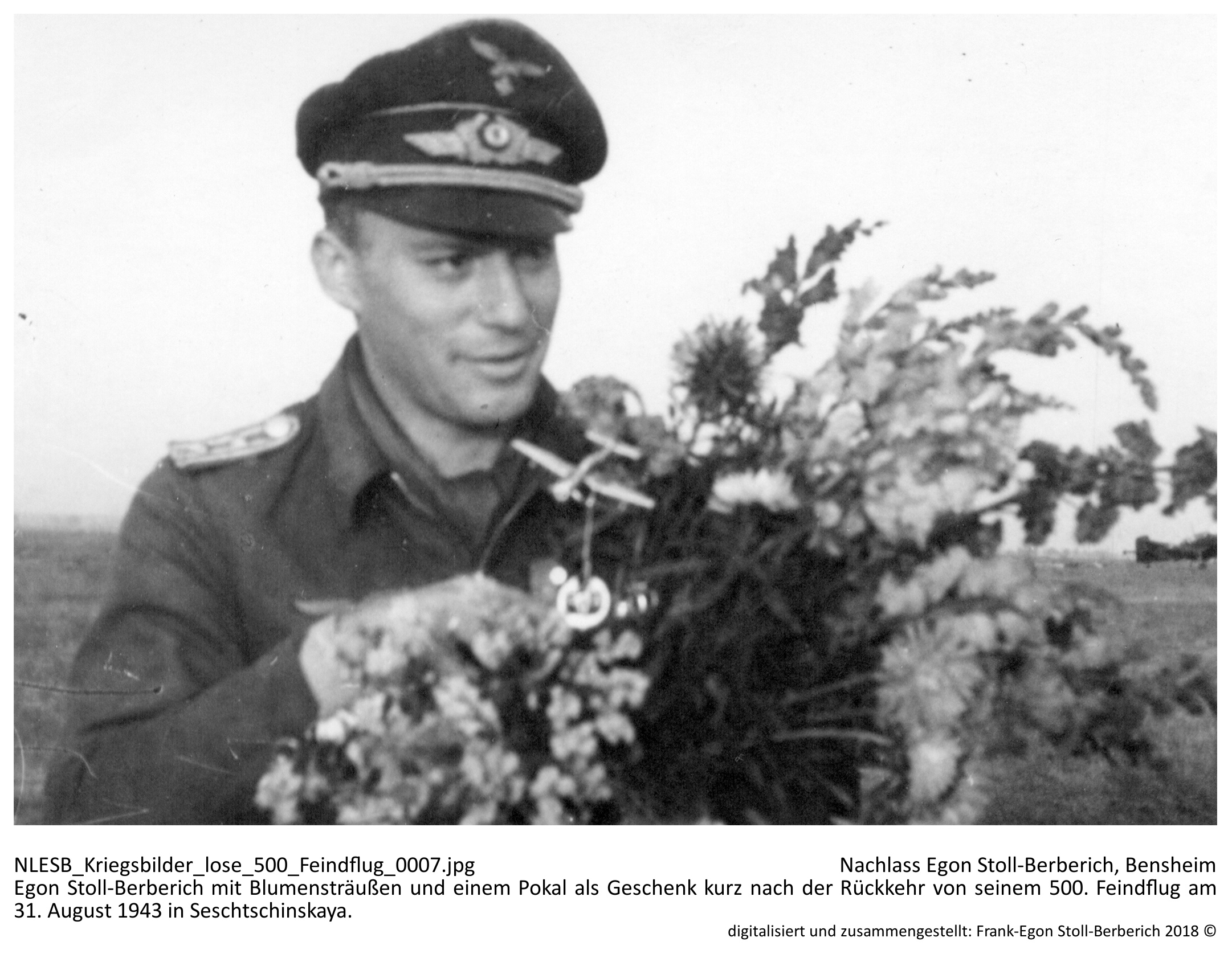 Egon Stoll-Berberich mit Blumensträußen und einem Pokal als Geschenk kurz nach der Rückkehr von seinem 500. Feindflug am 31. August 1943 in Seschtschinskaya. Egon Stoll-Berberich mit Blumensträußen und einem Pokal als Geschenk kurz nach der Rückkehr von seinem 500. Feindflug am 31. August 1943 in Seschtschinskaya. NLESB_Kriegsbilder_lose_500_Feindflug_0007.