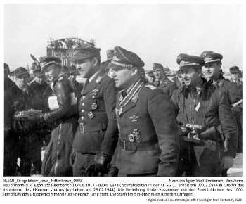 Hauptmann d.R. Egon Stoll-Berberich (17.06.1913 - 02.05.1973), Staffelkapitän in der III. SG 1,  erhält am 07.03.1944 in Orscha das Ritterkreuz des Eisernen Kreuzes (verliehen am 29.02.1944). Die Verleihung findet zusammen mit den Feierlichkeiten des 1000. Feindflugs des Gruppenkommandeurs Friedrich Lang statt. Die Staffel mit ihrem neuen Ritterkreuzträger. NLESB_Kriegsbilder_lose_Ritterkreuz_0008