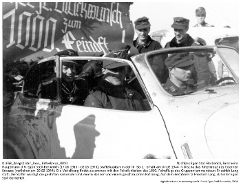 Hauptmann d.R. Egon Stoll-Berberich (17.06.1913 - 02.05.1973), Staffelkapitän in der III. SG 1,  erhält am 07.03.1944 in Orscha das Ritterkreuz des Eisernen Kreuzes (verliehen am 29.02.1944). Die Verleihung findet zusammen mit den Feierlichkeiten des 1000. Feindflugs des Gruppenkommandeurs Friedrich Lang statt. Die Staffel würdigt die geehrten Kameraden mit einem Banner und einem geschmückten Fahrzeug. Auf dem Beifahrersitz Friedrich Lang, dahinter Egon Stoll-Berberich. NLESB_Kriegsbilder_lose_Ritterkreuz_0010