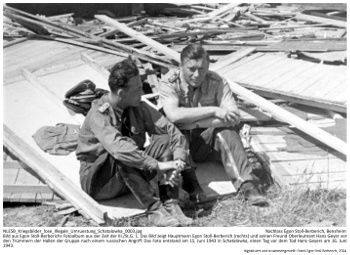 Bild aus Egon Stoll-Berberichs Fotoalbum aus der Zeit der III./St.G. 1. Das Bild zeigt Hauptmann Egon Stoll-Berberich (rechts) und seinen Freund Oberleutnant Hans Geyer vor den Trümmern der Hallen der Gruppe nach einem russischen Angriff. Das Foto entstand am 15. Juni 1943 in Schatalowka, einen Tag vor dem Tod Hans Geyers am 16. Juni 1943. NLESB_Kriegsbilder_lose_Illegale_Umruestung_Schatalowka_0003.